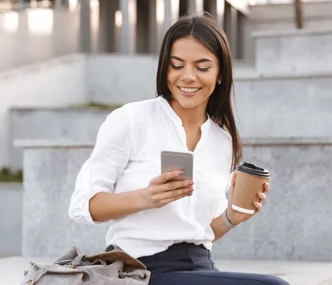 a person holding a coffee and checking their phone